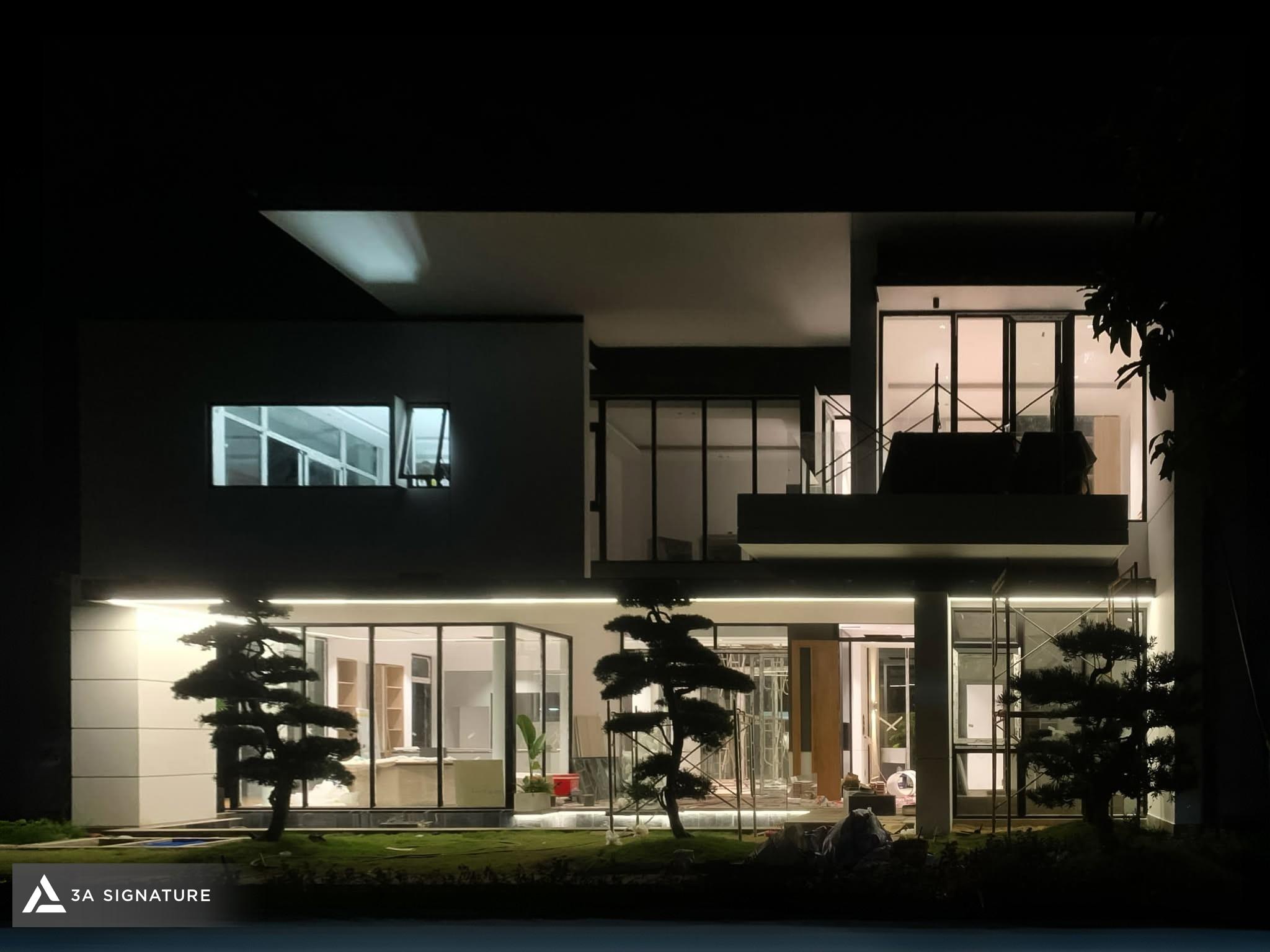 Hoàn thiện biệt thự Modern Tropical với đèn hắt mặt tiền giúp nhấn mạnh khối kiến trúc, mảng kính và cảnh quan xanh trong không gian đêm.