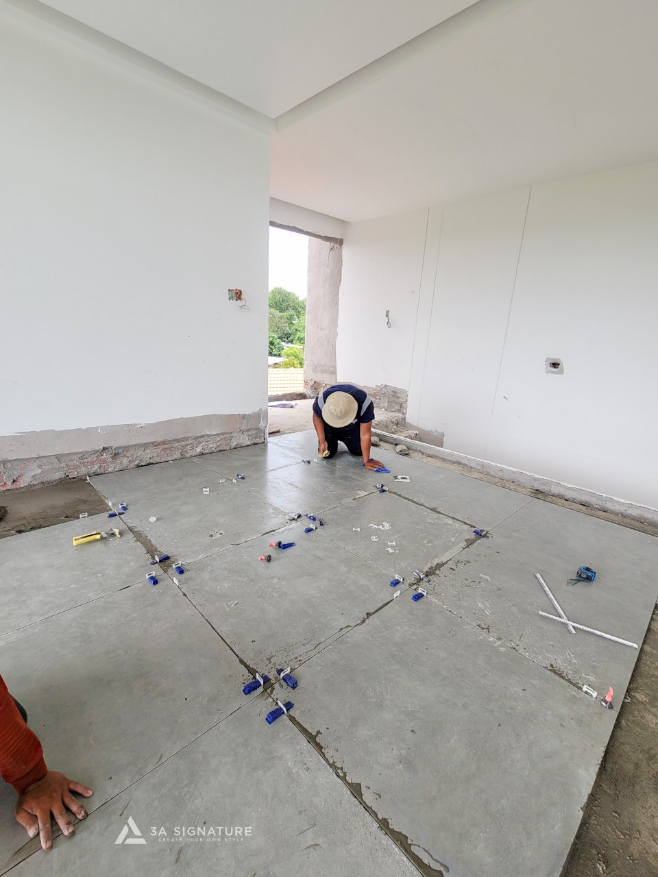 Nhân viên thi công đang căn chỉnh ron gạch sàn bằng ke ron tại công trình biệt thự H-Villa, đảm bảo các đường mạch thẳng hàng và đều nhau.