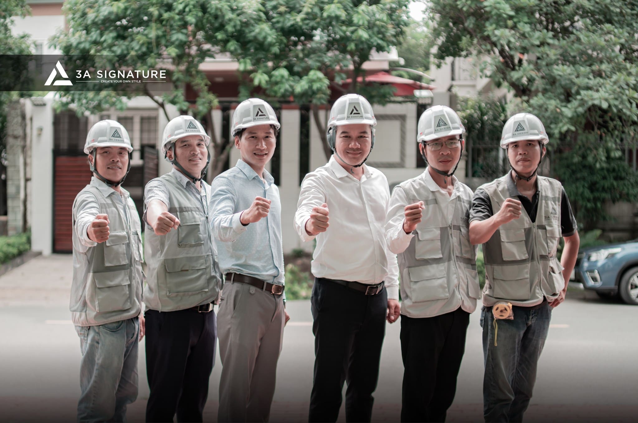 Nhóm kỹ sư và kiến trúc sư của 3A Signature trong trang phục công trình và mũ bảo hộ, tạo dáng thể hiện sự quyết tâm trước biệt thự Tropical Modern đang thi công.