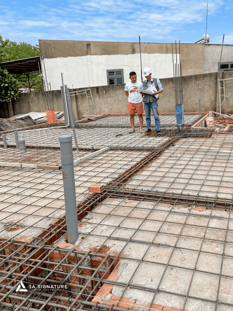 Thi Công Biệt Thự Green Villa – Giai Đoạn Đổ Bê Tông Móng Chuẩn Kỹ Thuật Kỹ sư và chủ nhà kiểm tra hệ thống cốt thép móng tại công trình xây dựng, các thanh thép được lắp đặt chính xác theo bản vẽ kỹ thuật.