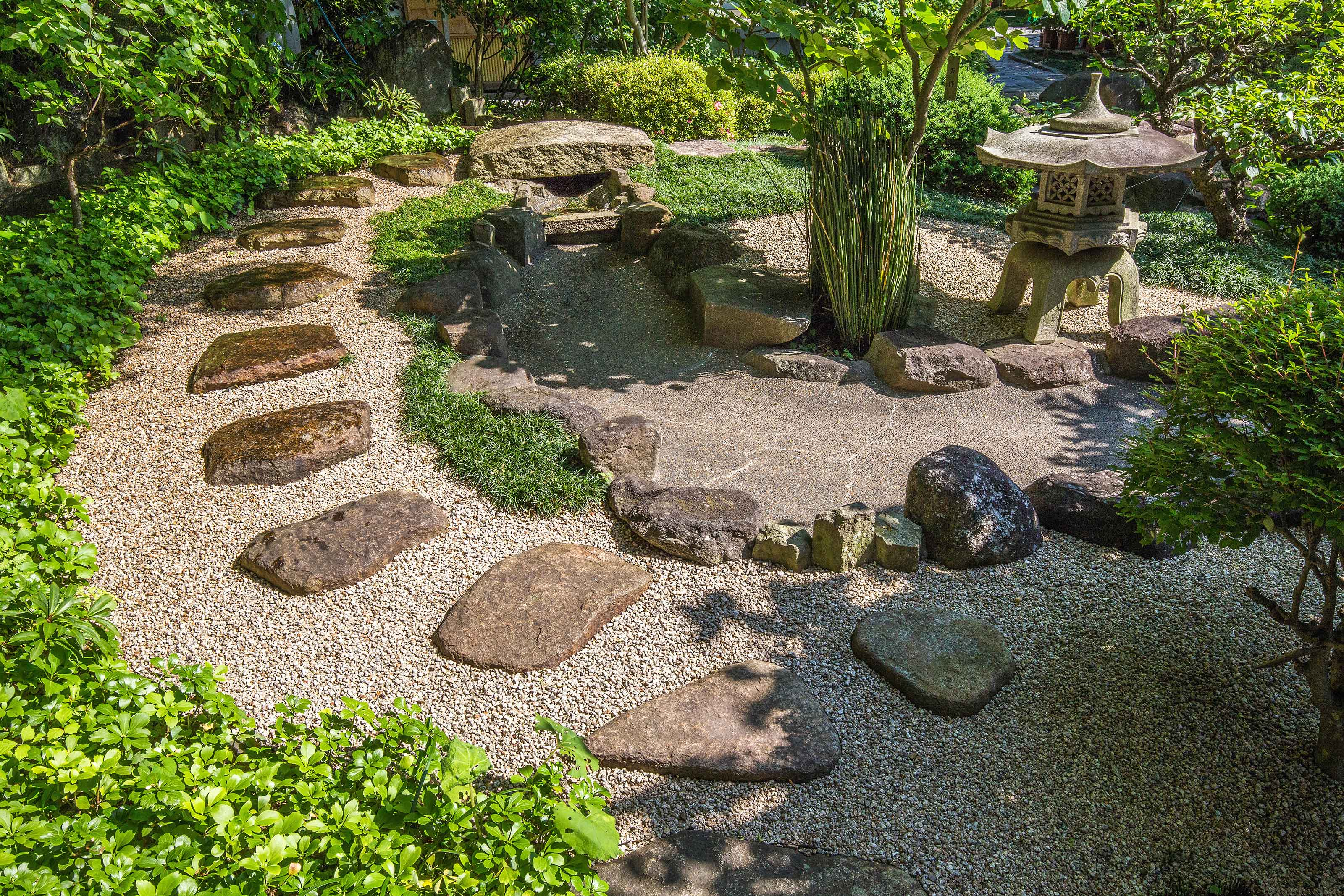 Zen rock garden with stone pathways, gravel, moss, and sculptural elements, showcasing a calming outdoor space ideal for Tropical Modern villa environments.