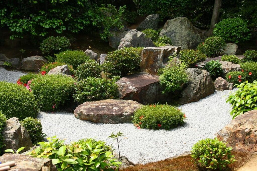 Zen Rock Garden Ideas To Bring Balance And Harmony Home A lush zen rock garden featuring natural stones, green shrubs, and white gravel paths, blending calm minimalism with tropical greenery for a balanced villa landscape.