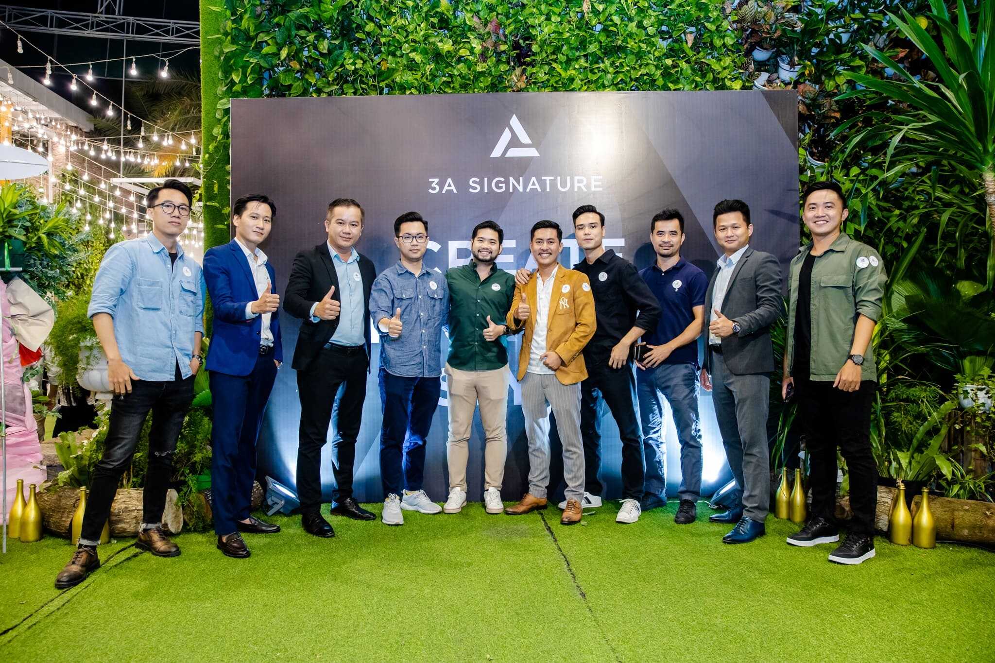 Đội ngũ 3A Signature chụp ảnh kỷ niệm trong sự kiện đánh dấu 5 năm thành lập, đứng trước backdrop thương hiệu giữa không gian xanh rực rỡ.